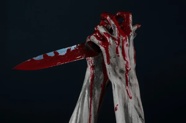 Bloody Halloween theme: zombie killer holding a large bloody knife isolated on black background in studio. — Stock Photo, Image