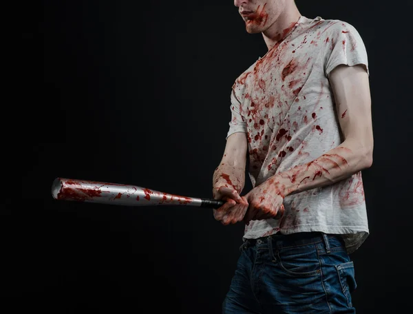 Bloody topic: The guy in a bloody T-shirt holding a bloody bat on a black background — Stock Photo, Image