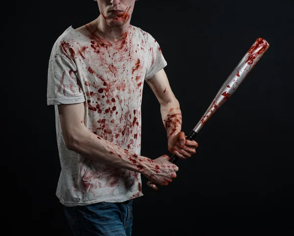 Bloody topic: The guy in a bloody T-shirt holding a bloody bat on a black background — Stock Photo, Image