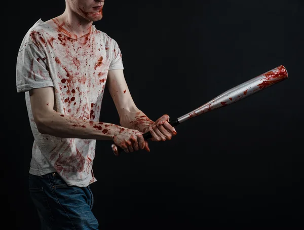Кровавая тема: парень в окровавленной футболке с кровавой битой на черном фоне — стоковое фото