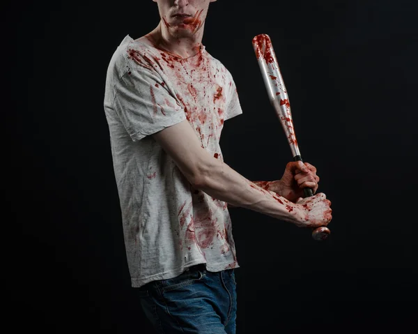 Bloody topic: The guy in a bloody T-shirt holding a bloody bat on a black background — Stock Photo, Image