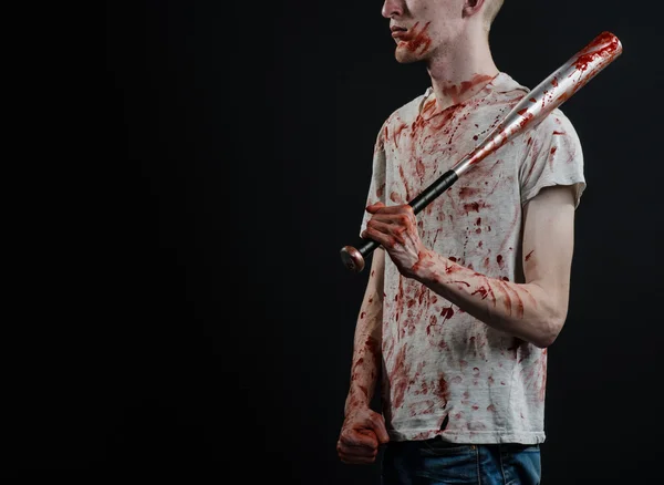 Bloody topic: The guy in a bloody T-shirt holding a bloody bat on a black background — Stock Photo, Image