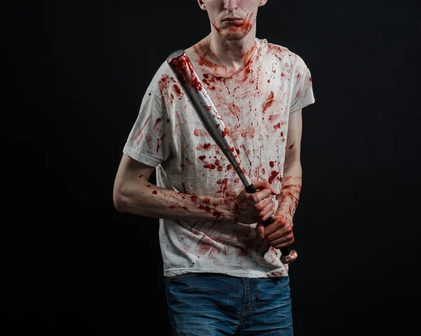Tópico sangrento: O cara com uma camiseta sangrenta segurando um bastão sangrento em um fundo preto — Fotografia de Stock