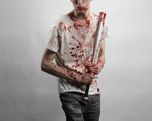 Tema sangriento: El tipo con una camiseta ensangrentada sosteniendo un murciélago ensangrentado sobre un fondo blanco — Foto de Stock
