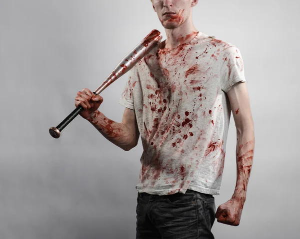 Sujet sanglant : Le gars en t-shirt sanglant tenant une batte sanglante sur un fond blanc — Photo