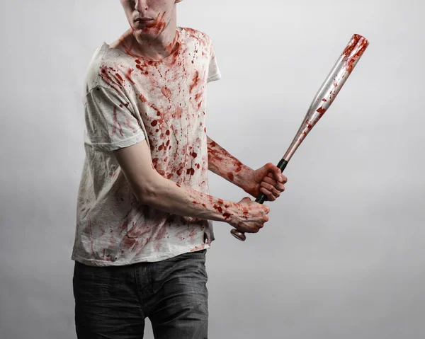 Tema sangriento: El tipo con una camiseta ensangrentada sosteniendo un murciélago ensangrentado sobre un fondo blanco — Foto de Stock