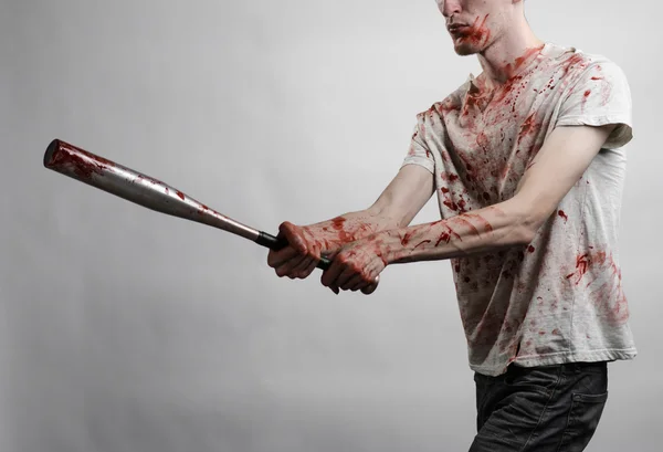 Bloody topic: The guy in a bloody T-shirt holding a bloody bat on a white background — Stock Photo, Image