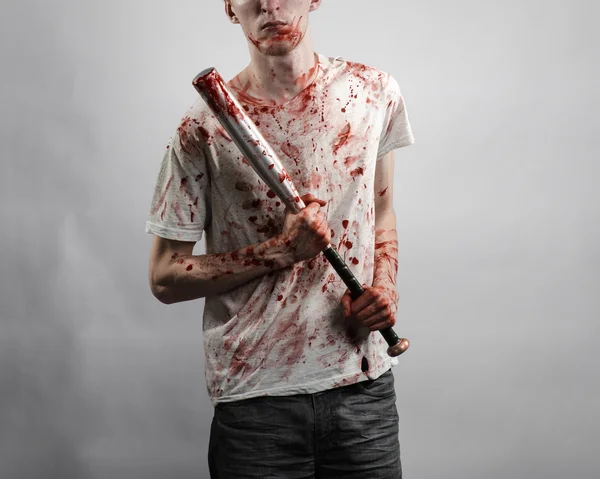 Argomento sanguinoso: Il ragazzo con una maglietta insanguinata con una mazza insanguinata su uno sfondo bianco — Foto Stock