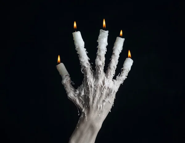 Halloween theme: on the hand wearing a candle and dripping melted wax on black isolated background