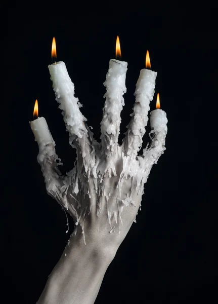 Halloween theme: on the hand wearing a candle and dripping melted wax on black isolated background