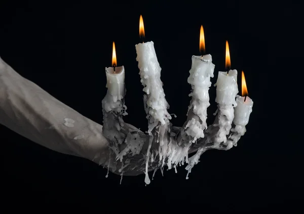 Halloween-Thema: auf der Hand eine Kerze und tropfendes geschmolzenes Wachs auf schwarzem, isoliertem Hintergrund — Stockfoto