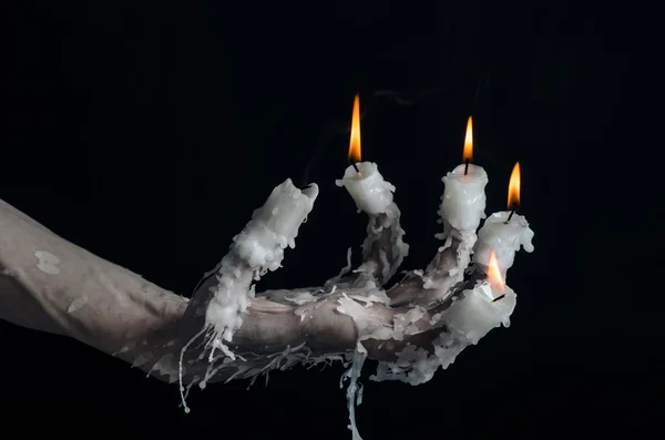 Halloween-Thema: auf der Hand eine Kerze und tropfendes geschmolzenes Wachs auf schwarzem, isoliertem Hintergrund — Stockfoto