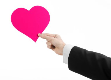 Sevgililer günü ve aşk şarkısı: Studio beyaz bir arka plan üzerinde izole bir pembe kalp tutan siyah elbiseli bir adam