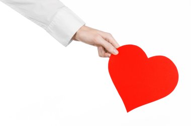 Heart Disease and Health Topic: hand doctor in a white shirt holding a card in the form of a red heart isolated on a white background in studio clipart