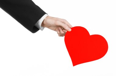 Sevgililer günü ve aşk şarkısı: Studio beyaz bir arka plan üzerinde izole kırmızı bir kalp tutan siyah elbiseli bir adam