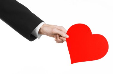 Sevgililer günü ve aşk şarkısı: Studio beyaz bir arka plan üzerinde izole kırmızı bir kalp tutan siyah elbiseli bir adam