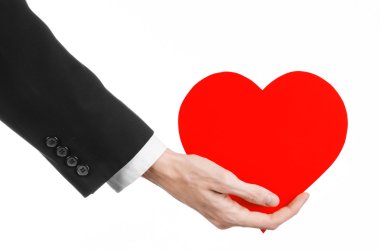 Sevgililer günü ve aşk şarkısı: Studio beyaz bir arka plan üzerinde izole kırmızı bir kalp tutan siyah elbiseli bir adam