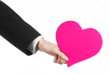 Sevgililer günü ve aşk şarkısı: Studio beyaz bir arka plan üzerinde izole bir pembe kalp tutan siyah elbiseli bir adam