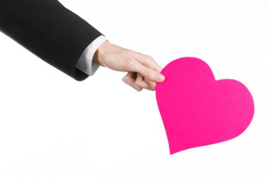 Sevgililer günü ve aşk şarkısı: Studio beyaz bir arka plan üzerinde izole bir pembe kalp tutan siyah elbiseli bir adam