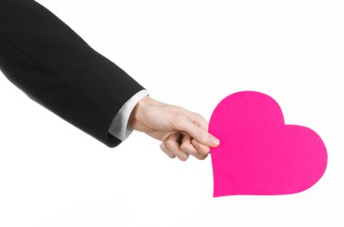 Sevgililer günü ve aşk şarkısı: Studio beyaz bir arka plan üzerinde izole bir pembe kalp tutan siyah elbiseli bir adam