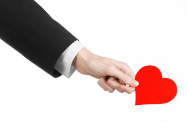 Sevgililer günü ve aşk şarkısı: Studio beyaz bir arka plan üzerinde izole kırmızı bir kalp tutan siyah elbiseli bir adam