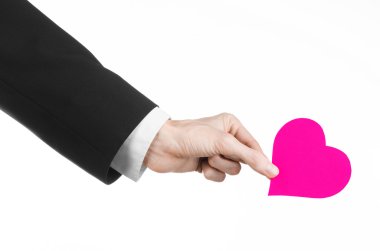 Sevgililer günü ve aşk şarkısı: Studio beyaz bir arka plan üzerinde izole bir pembe kalp tutan siyah elbiseli bir adam