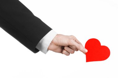 Sevgililer günü ve aşk şarkısı: Studio beyaz bir arka plan üzerinde izole kırmızı bir kalp tutan siyah elbiseli bir adam