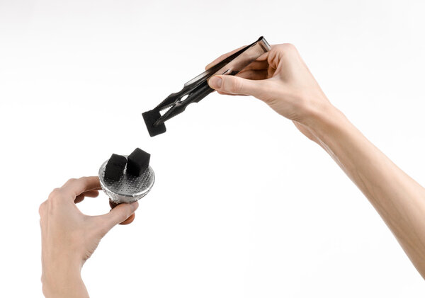 Hookah topic: Bartender holding a forceps with coal for hookah and puts them into a clay bowl isolated on white background