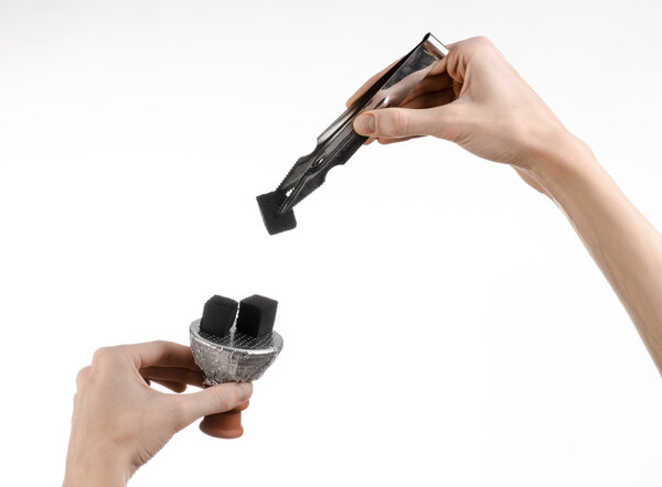 Hookah topic: Bartender holding a forceps with coal for hookah and puts them into a clay bowl isolated on white background