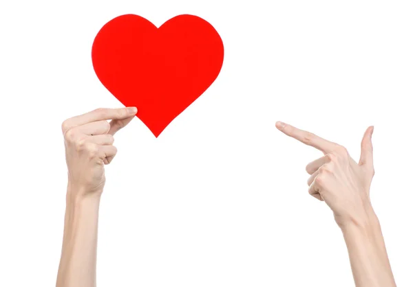 San Valentino e il tema dell'amore: mano che tiene un cuore rosso isolato su sfondo bianco in studio — Foto Stock