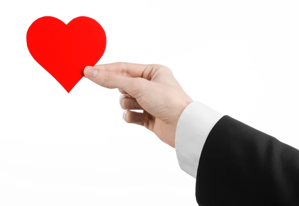 Valentine's Day and love theme: a man in a black suit holding a red heart isolated on a white background in studio — Stock Photo, Image