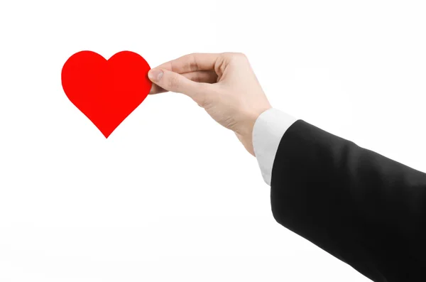 Tema del Día de San Valentín y el amor: un hombre con un traje negro sosteniendo un corazón rojo aislado sobre un fondo blanco en el estudio — Foto de Stock