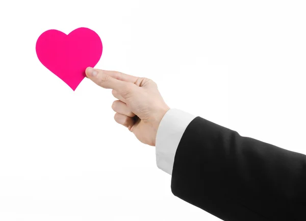 Valentinstag und Liebesthema: ein Mann im schwarzen Anzug mit einem rosafarbenen Herz auf weißem Hintergrund im Studio — Stockfoto