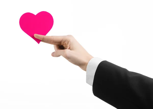 Dia dos Namorados e tema do amor: um homem de terno preto segurando um coração rosa isolado em um fundo branco no estúdio — Fotografia de Stock