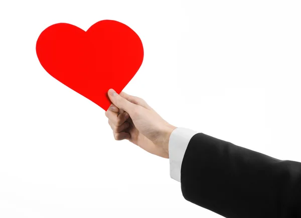 Valentine's Day and love theme: a man in a black suit holding a red heart isolated on a white background in studio — Stock Photo, Image