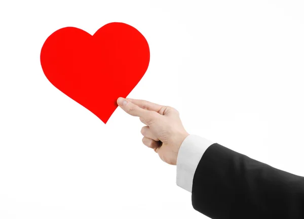 День святого Валентина и тема любви: мужчина в черном костюме, держащий красное сердце изолированным на белом фоне в студии — стоковое фото