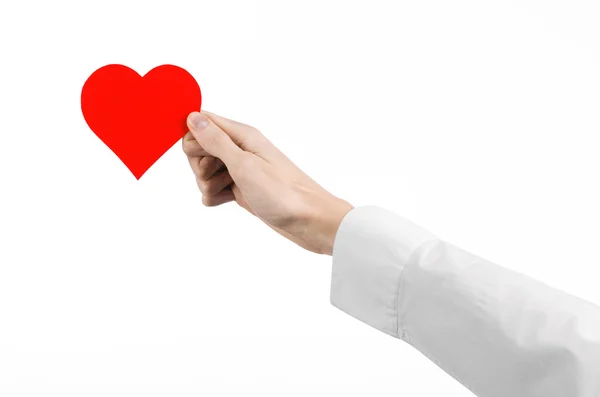 Tema de Enfermedades del Corazón y Salud: Médico de mano con una camisa blanca sosteniendo una tarjeta en forma de corazón rojo aislado sobre un fondo blanco en el estudio — Foto de Stock