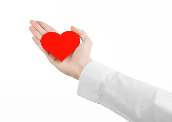 Doença cardíaca e saúde Tópico: médico de mão em uma camisa branca segurando um cartão na forma de um coração vermelho isolado em um fundo branco no estúdio — Fotografia de Stock