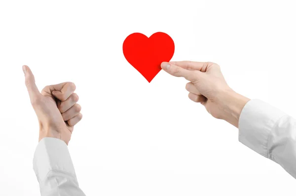 Tema de Enfermedades del Corazón y Salud: Médico de mano con una camisa blanca sosteniendo una tarjeta en forma de corazón rojo aislado sobre un fondo blanco en el estudio —  Fotos de Stock