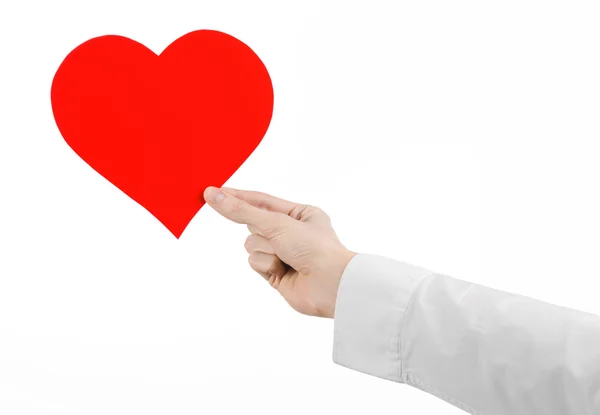 Tema de Enfermedades del Corazón y Salud: Médico de mano con una camisa blanca sosteniendo una tarjeta en forma de corazón rojo aislado sobre un fondo blanco en el estudio —  Fotos de Stock