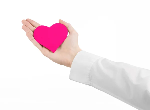 Tema de Enfermedades del Corazón y Salud: Médico de mano con una camisa blanca sosteniendo una tarjeta en forma de corazón rosa aislado sobre un fondo blanco en el estudio —  Fotos de Stock