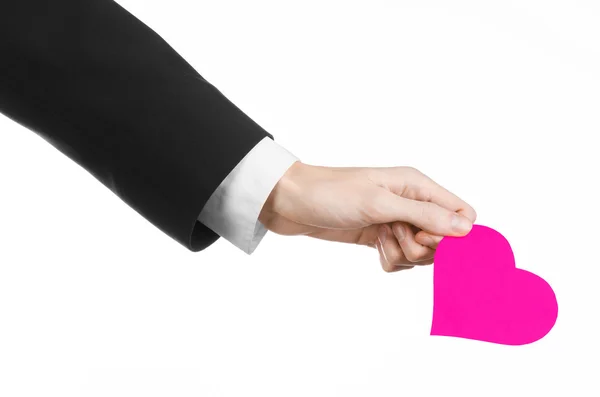 Valentine's Day and love theme: a man in a black suit holding a pink heart isolated on a white background in studio — Stock Photo, Image