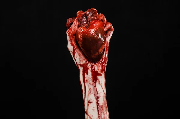 Blut und Halloween-Thema: schrecklich blutige Hand hält abgerissenes blutendes Menschenherz isoliert auf schwarzem Hintergrund im Studio — Stockfoto