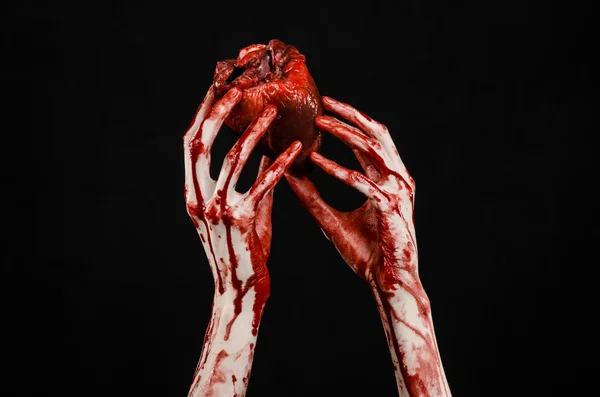 Sangue e tema de Halloween: mão sangrenta terrível segurar rasgado sangramento coração humano isolado no fundo preto no estúdio — Fotografia de Stock