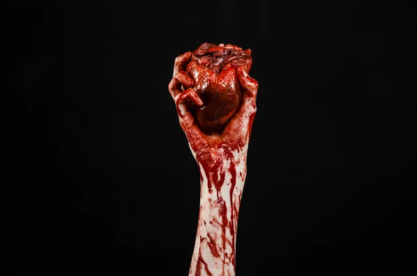 Blut und Halloween-Thema: schrecklich blutige Hand hält abgerissenes blutendes Menschenherz isoliert auf schwarzem Hintergrund im Studio — Stockfoto