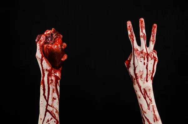 Blood and Halloween theme: terrible bloody hand hold torn bleeding human heart isolated on black background in studio — Stock Photo, Image