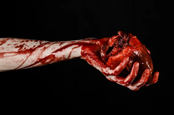 Blut und Halloween-Thema: schrecklich blutige Hand hält abgerissenes blutendes Menschenherz isoliert auf schwarzem Hintergrund im Studio — Stockfoto