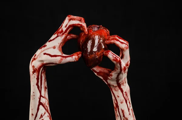 Sangue e tema de Halloween: mão sangrenta terrível segurar rasgado sangramento coração humano isolado no fundo preto no estúdio — Fotografia de Stock