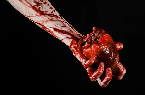 Sânge și tema de Halloween: mână sângeroasă teribilă ține rupt sângerare inima umană izolat pe fundal negru în studio — Fotografie, imagine de stoc