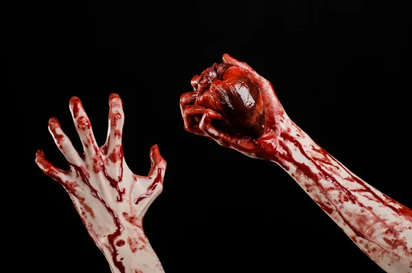 Кровавая тема и тема Хэллоуина: жуткая кровавая рука держит разорванное кровоточащее человеческое сердце изолированным на черном фоне в студии — стоковое фото